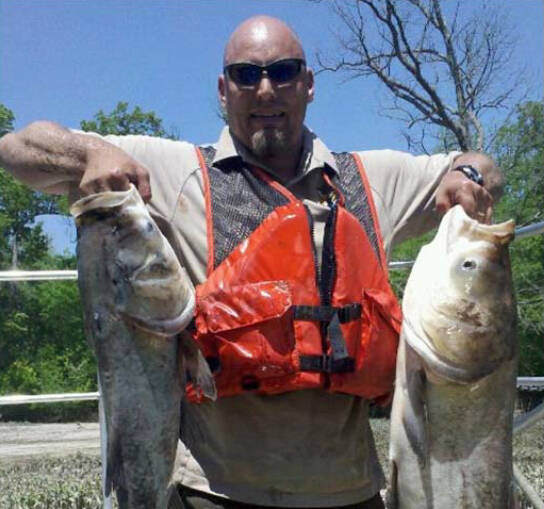 AWRI distinguished alumnus Aaron Parker holds two large bass, one in each hand.